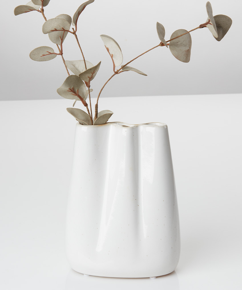 Hvid vase med organiske linjer og kunstig gren