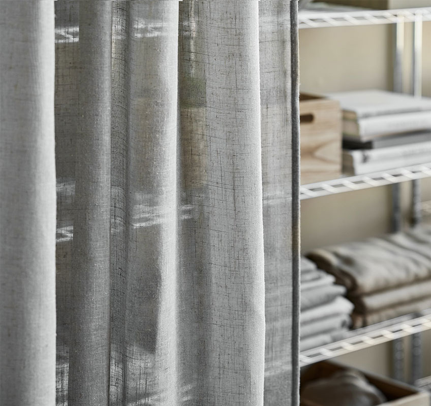 Reol i metal med grå gennemsigtige gardiner foran