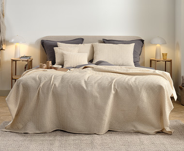 Soveværelse med seng dækket af beige sengetæppe