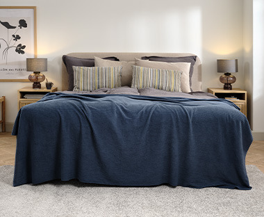 Soveværelse med seng dækket af blåt fleece sengetæppe