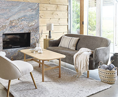 Sofa, sofabord og lænestol i stue med pejs og stort vindue