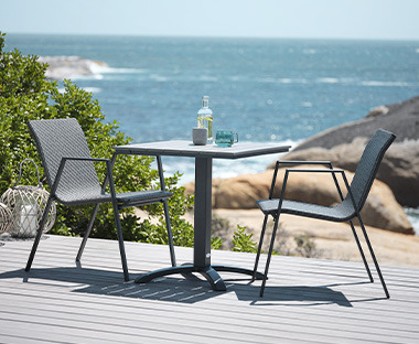 Cafébord med to stole i grå ved strand