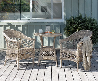 Cafébord med to matchende havestole i natur på terrasse
