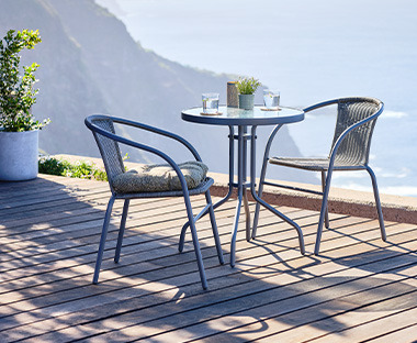Cafébord med to stole i grå på terrasse ved havet