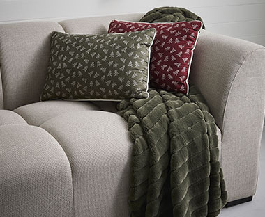 Sofa med grøn plaid og pyntepuder i rød og grøn
