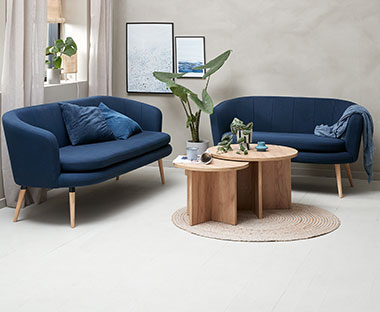 Stue med to mørkeblå sofaer og to runde sofaborde