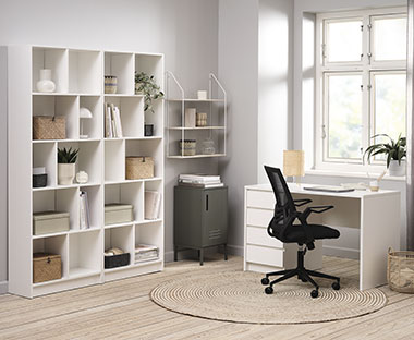Hvidt skrivebord, sort kontorstol og hvid reol i kontor 