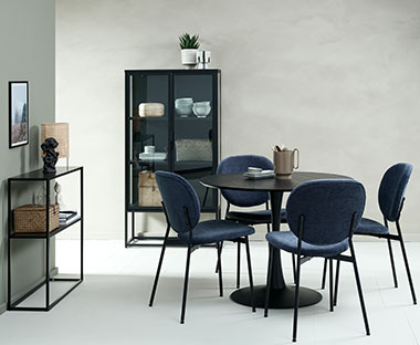 Rundt spisebord med fire spisebordsstole, sort vitrineskab og konsolbord