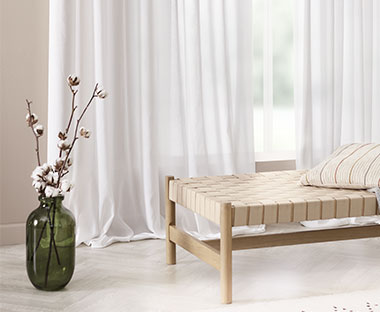 Hvide gardiner i lys stue med daybed i træ