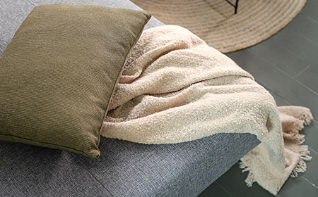 Tæpper, plaider og pyntepuder skaber hygge i dit hjem