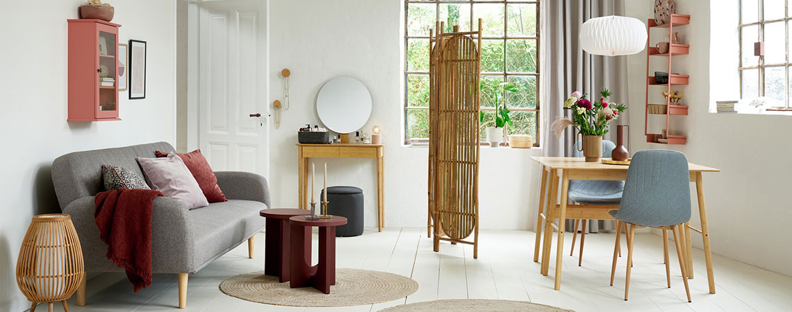 Stue/spisestue med rosa vægskab, grå sovesofa, påklædningsskærm i bambus, skrivebord i bambus og grå spisebordsstole 