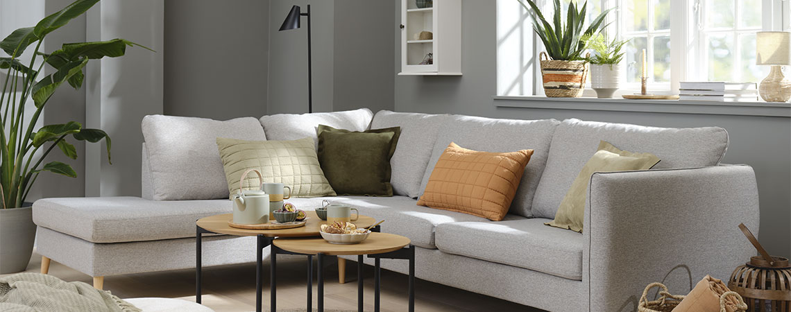 Stue med grå sofa og orange, grønne og beige hynder
