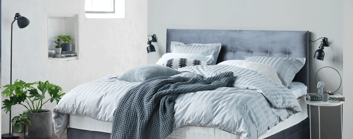 Soveværelse med seng, madras, topmadras og lyseblå dyner og puder