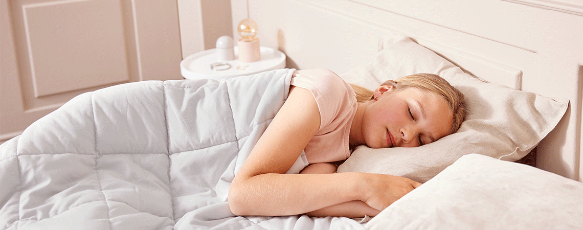 Pige sover på siden i en seng med tyngdedyne