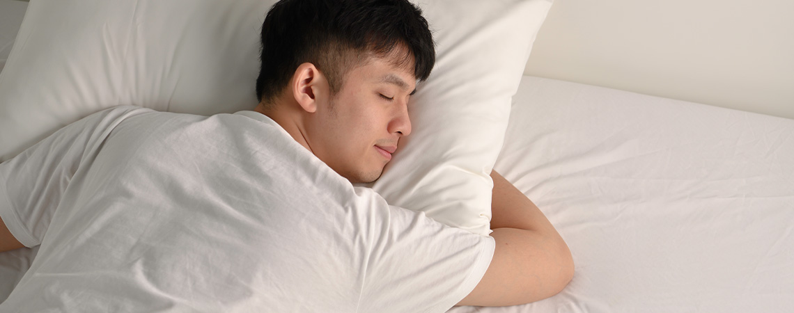 Mand sover roligt i en seng med hvid topmadras, der ikke skrider