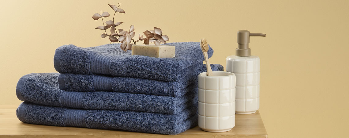 Blå håndklæder på en bænk med en tandbørsteholder og en sæbedispenser