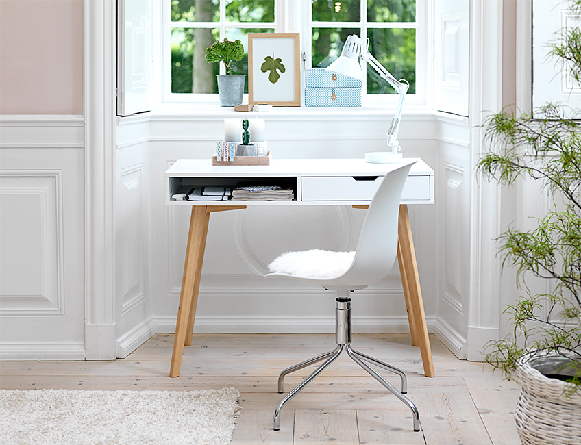 Hvidt skrivebord med træ ben ved vindue i lys stue