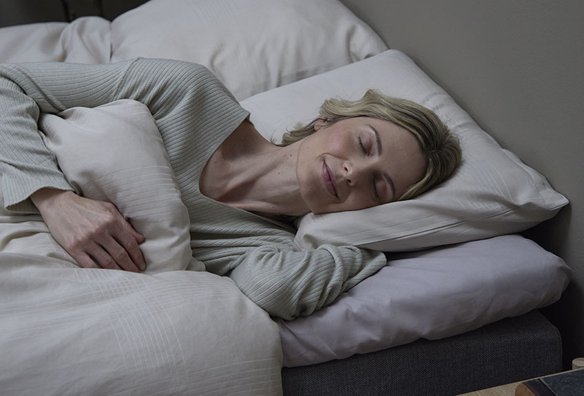 Smiling woman sleeping in bed after being guided on how to buy a bed