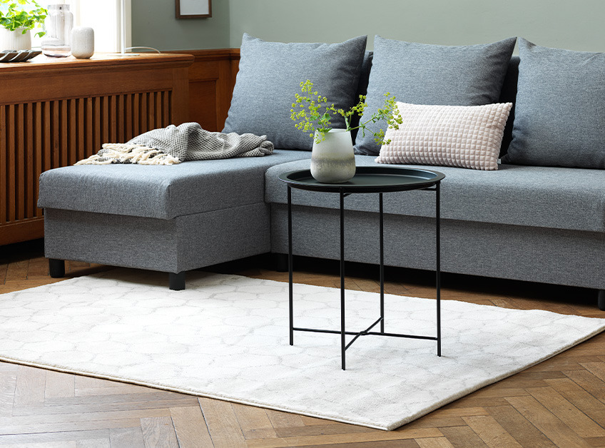 Lille sofabord i sort foran grå sofa