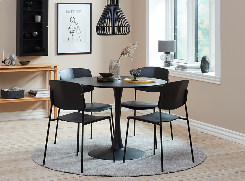 Rundt og sort spisebord med fire sorte spisebordsstole