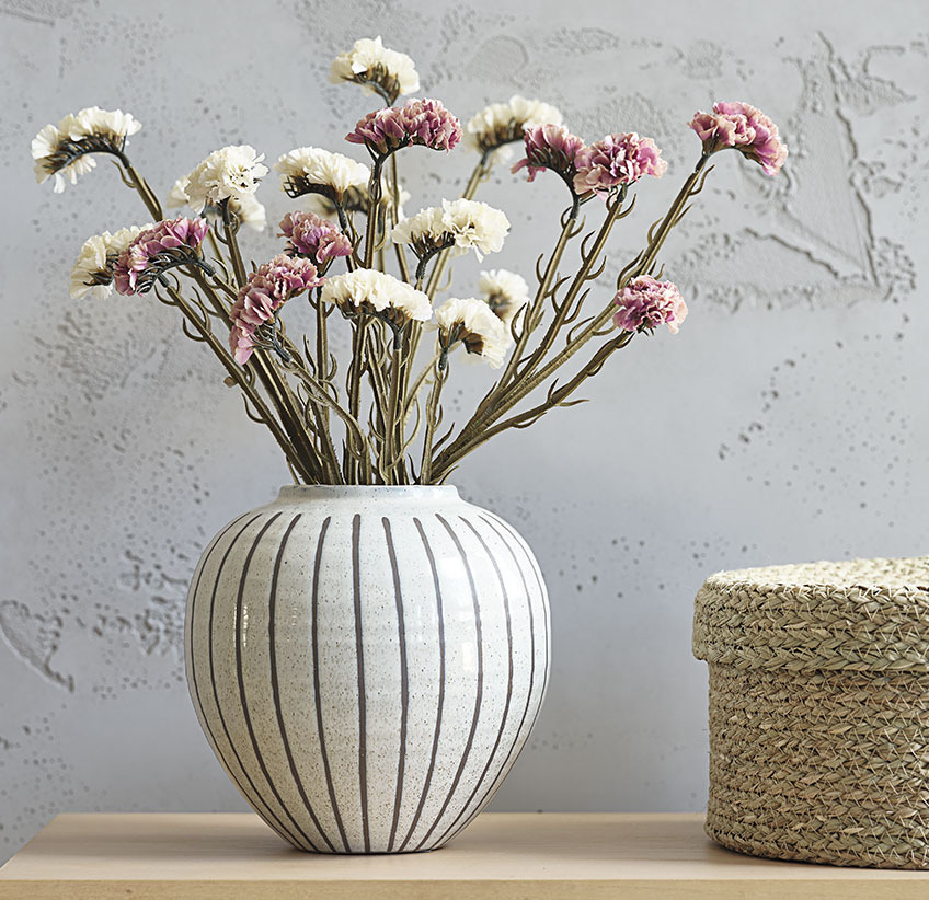 Kunstige blomster i rosa og hvid i hvid vase med grå striber