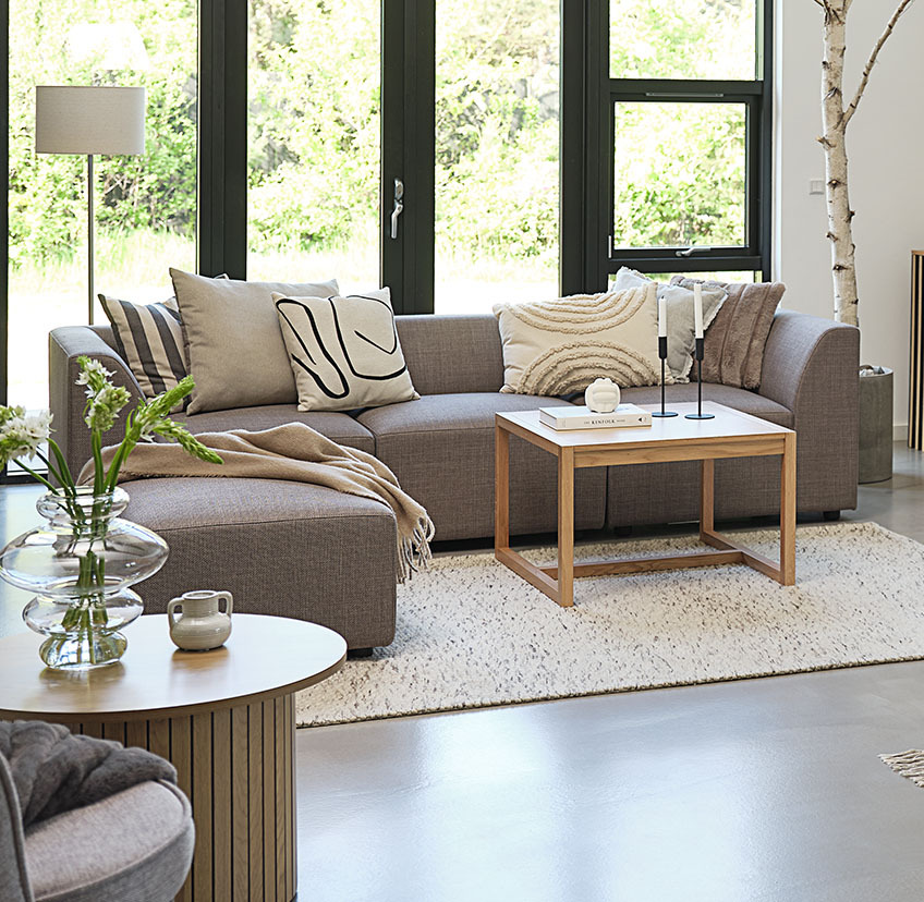 Minimalistisk sofabord egetræ i lys stue med stor sofa og pyntepuder