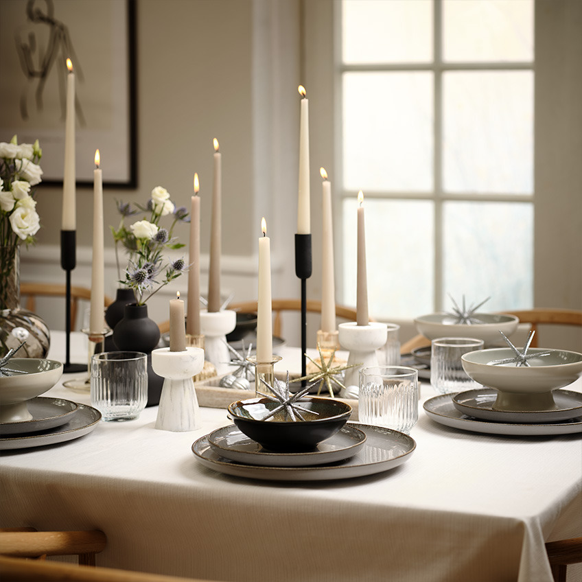 Bord dækket med tallerkener, glas, skåle og stearinlys 