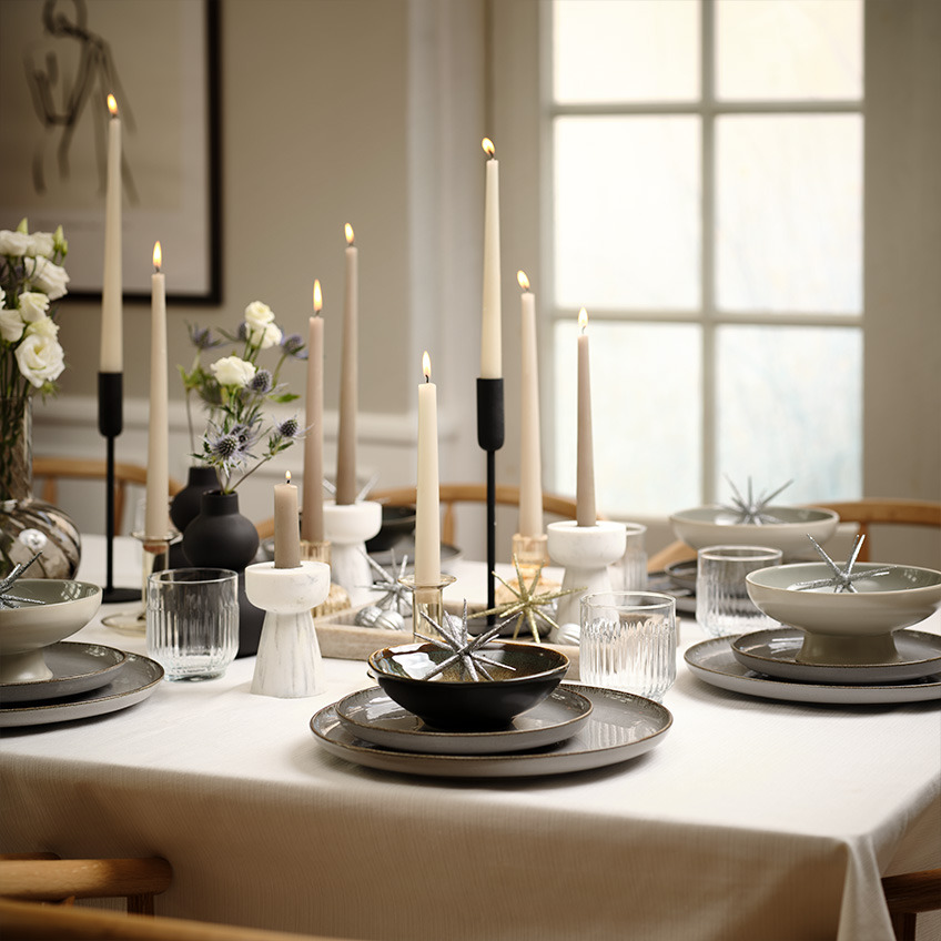 FERDUS-tallerkener, JOEL-skåle på fod og OLAV-lysestage Bord dækket med tallerkener, glas, skåle og stearinlys