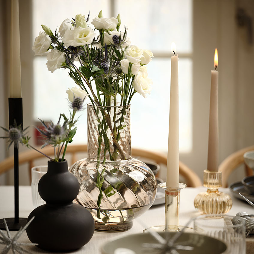 Vase med blomster og snoet stearinlys