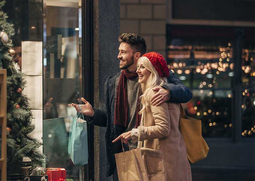 Julegaveshopping i selskab med dem, du holder af, er ren hygge Et par smiler mens de handler ind til julegaver