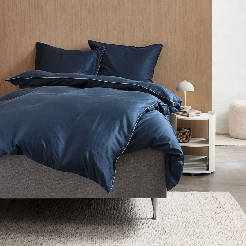 Bomuldssatin og viskose af bambus sengetøj i mørkeblå på en seng i soveværelse  