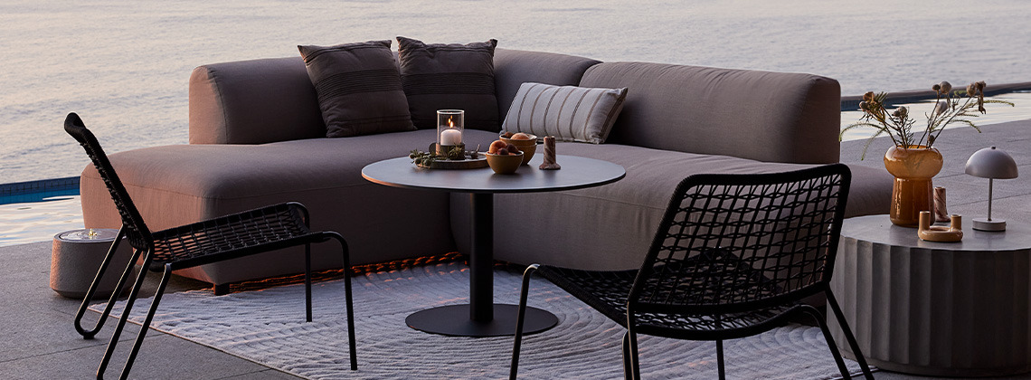Modstandsdygtig og hurtigtørrende loungesofa og haveloungestole på terrasse ved solnedgang