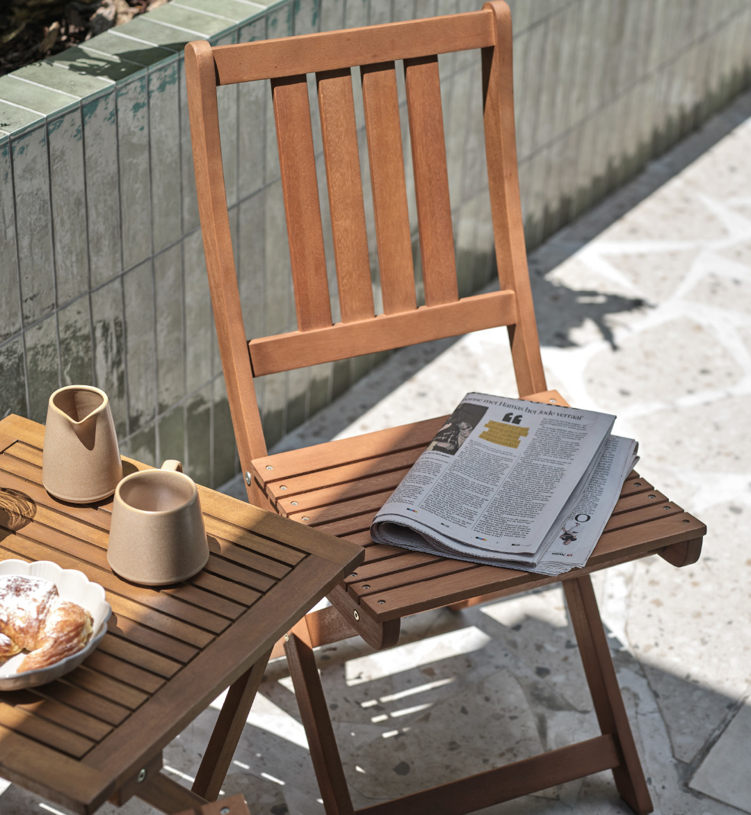 Klapstol og cafébord EGELUND i træ med kaffe, kage og dagens avis