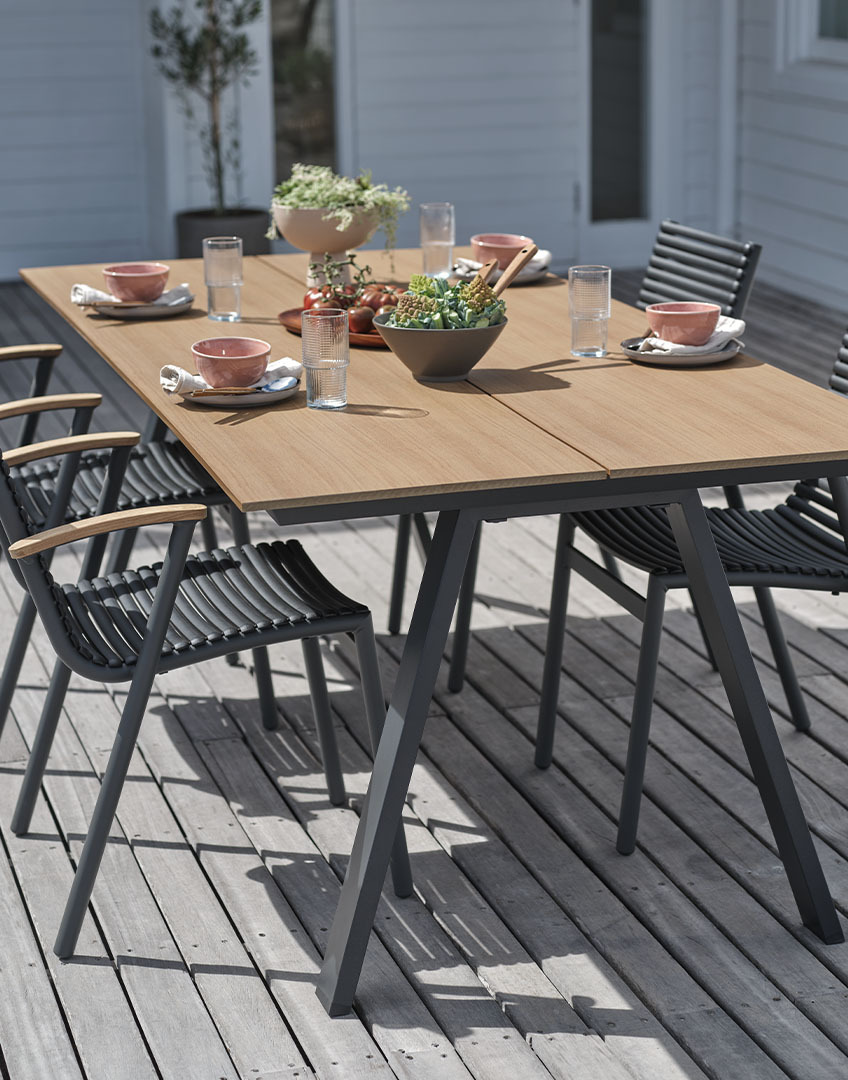 Havebord med bordplade i kunstigt træ samt stabelstole til haven i plast og genanvendt teak 