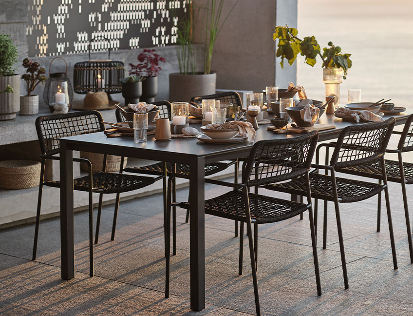 Havebord og havestole med opdækket bord på terrasse ved solnedgang