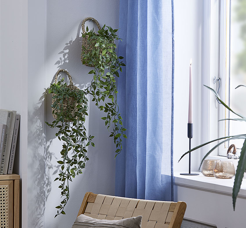 To kurve med kunstige planter hængende på en stuevæg