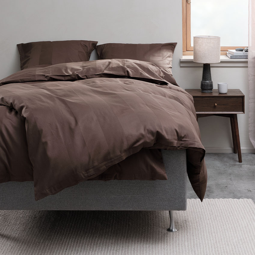 Dyb mørkebrunt sengesæt af bomuld og bambusviskose på seng i soveværelse 