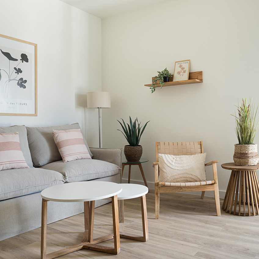 VADEHAVET lænestol, SVENSTRUP borde, KRISTOF gulvlampe, TORD billedramme, JYSTED væghylde, NATTLILJA pude og GODSKE falsk plante. Stueområde med sofa, lænestol, sofaborde og dekorationer.