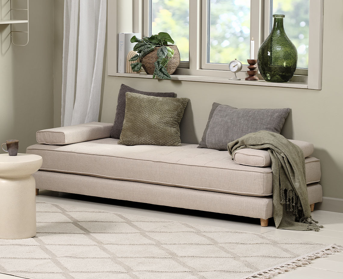 Beige daybed i stue med plaid og pyntepuder 