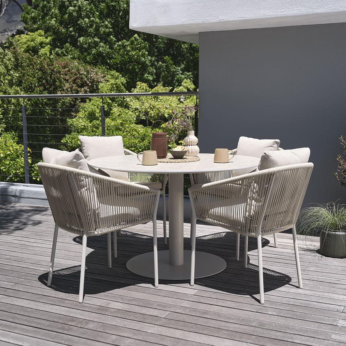 VAMDRUP havebord og BRAVA havestole Rundt havebord på sokkel og fire havestole på en terrasse