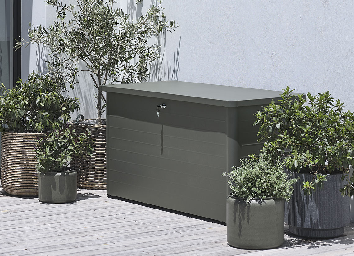DREJET hyndeboks Grå hyndeboks på en lille terrasse med planter