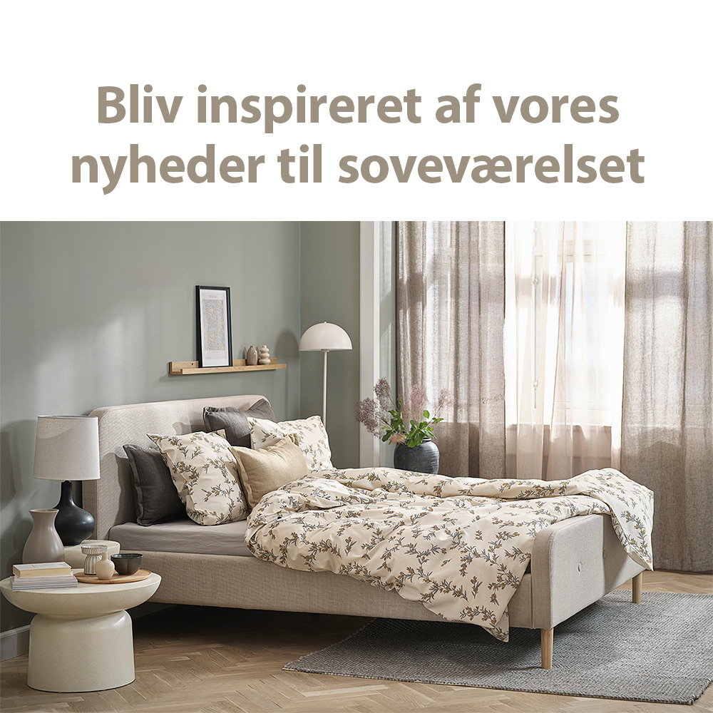 Lyst soveværelse med nyopredt seng og lyst sengebord