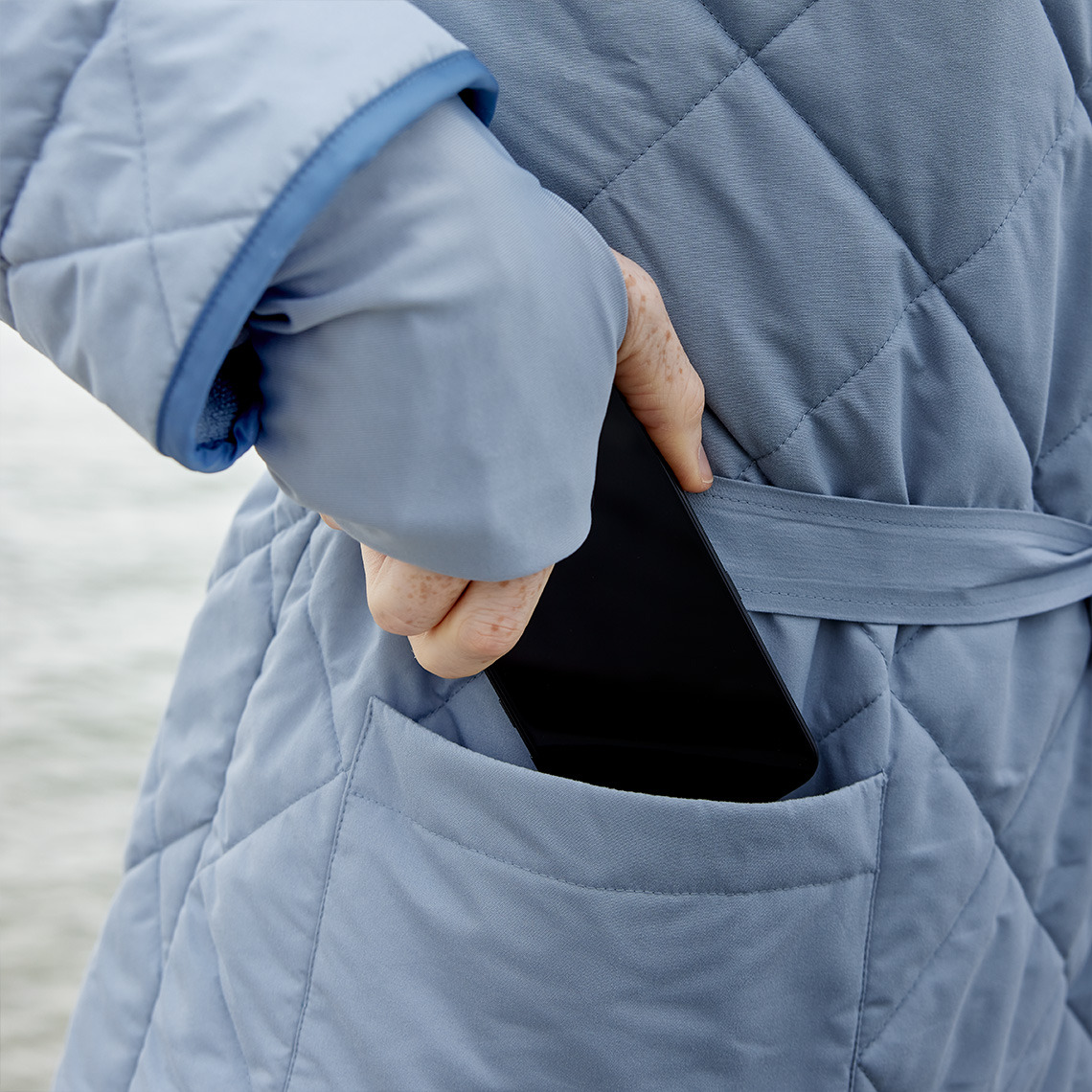 OSBY har store indvendige og udvendige lommer Person, der tager sin mobiltelefon i lommen på badekåbe