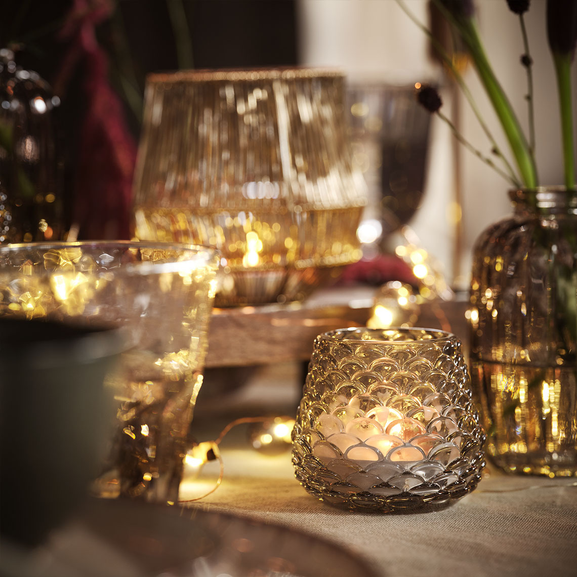 Spisebord oplyst af stearinlys og fyrfadslys i fyrfadslysholdere og lyskæder 