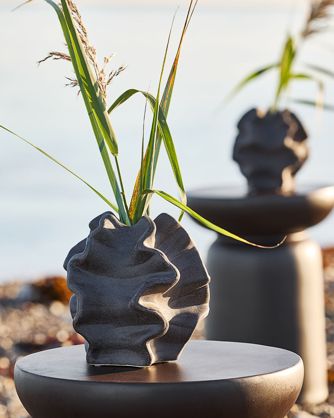 Organisk formet vase på piedestal på en strand