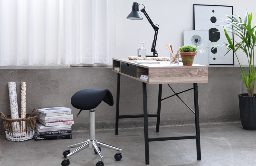 Lyst kontor med kontorstol, skrivebord og plakater