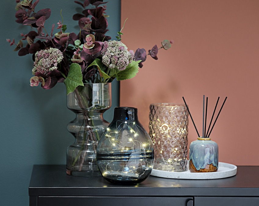 Vaser med lyskæder og blomster på et bord