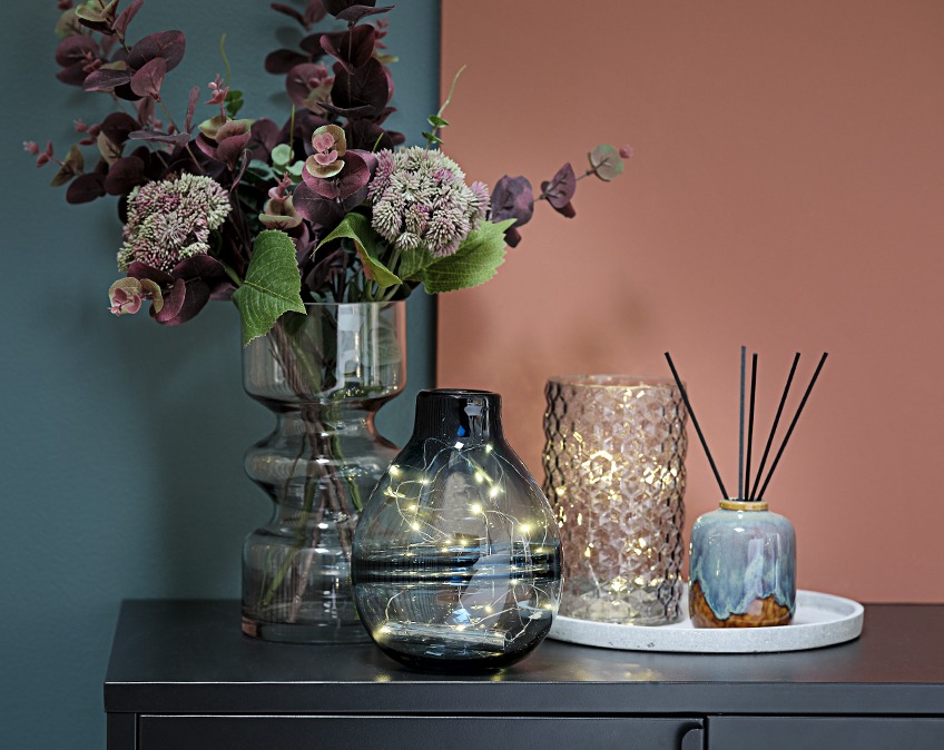 FOSS og VICTOR vase med MADS EMIL lyskæde og MANFRED vase med EJNER blomster Vaser med lyskæder og blomster på et bord