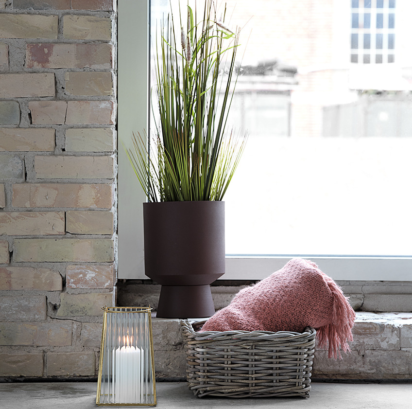 JOHN blomsterpotte med GODSKE kunstig plante TOMMY lanterne, og EIDE kurv med LINNEA plaid Blomsterpotte med kunstig plante, lanterne, og kurv med rosa plaid foran et vindue
