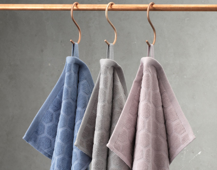 Håndklæder i tre farver hængende fra en stang